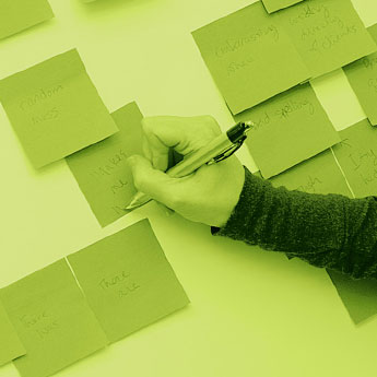 Person organizing their thoughts on post-it notes on a wall.